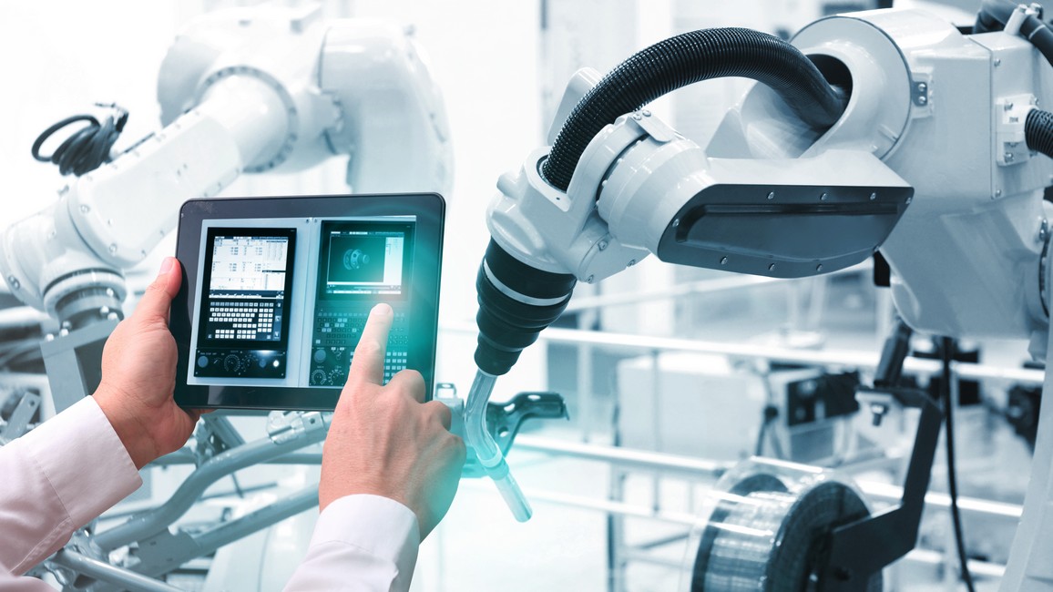 Mann bewegt mit Tablet einen Roboterarm.